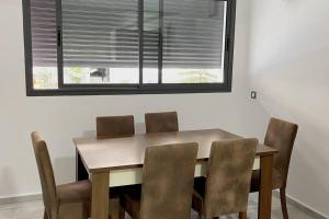 a dining room table with chairs and a window at Magnifique duplex moderne à 1 minute à pied de la plage- Résidence Miramar Mohammedia in Mohammedia