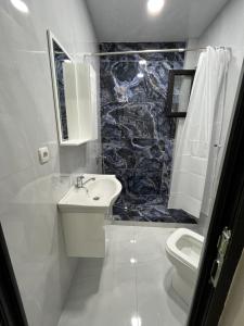 a white bathroom with a sink and a toilet at MT House in Batumi