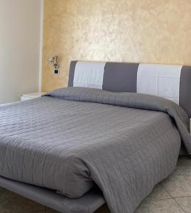 um quarto com uma cama grande e um edredão cinzento em Appartamenti Nataly em Nago-Torbole