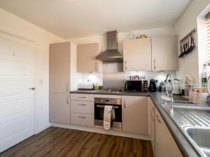 cocina con armarios blancos y fogones en Pass the Keys Stunning Newcastle Home en Elswick
