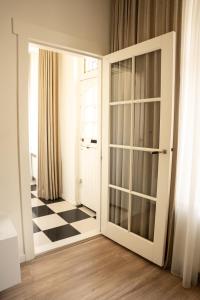 eine offene Tür in einem Zimmer mit kariertem Boden in der Unterkunft Kapiteinshuisje in Harderwijk