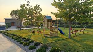 a playground with a slide and benches in a park at Real Life Homes luxurious seafront villas each with their own private pools in Korakokhórion