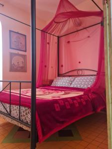 - une chambre avec un lit à baldaquin aux murs roses dans l'établissement Dar Alouane, à Essaouira