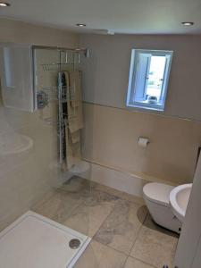 a bathroom with a shower and a toilet and a window at Cottage in Matlock, Derbyshire. Lower Holly Barn in Matlock Bank