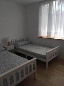 1 dormitorio con 2 camas y una ventana con cortinas en LA MARINA en Galizano