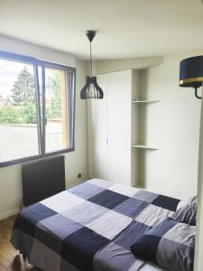 een slaapkamer met een blauw en wit bed en een raam bij Sara in Aulnay-sous-Bois