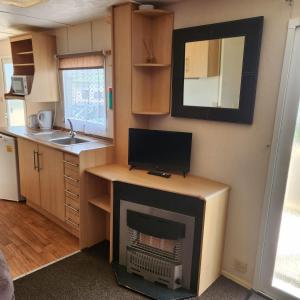 a small kitchen with a fireplace in a tiny house at 3 BEDROOM CARAVAN AT THE GRANGE HOLIDAY PARK, CHAPEL ROAD INGOLDMELLS in Addlethorpe