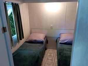 Duas camas num pequeno quarto com uma janela em MOBIL HOME em Faux-la-Montagne