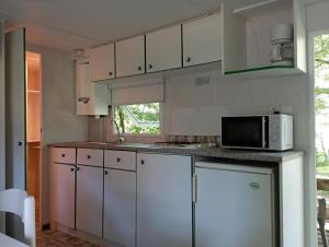a kitchen with white cabinets and a microwave at MOBIL HOME in Faux-la-Montagne
