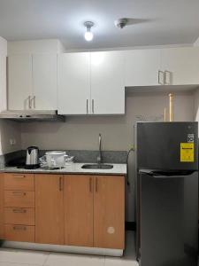 a kitchen with white cabinets and a black refrigerator at Spacious 1 bedroom unit in Araneta Center Cubao in Manila