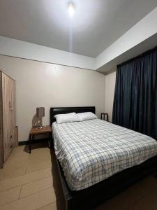 a bedroom with a bed with a blue curtain at Spacious 1 bedroom unit in Araneta Center Cubao in Manila