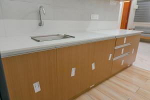 a kitchen with a sink and wooden cabinets at IZEL CASA Near Amrita Hospital in Cochin