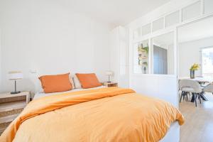1 dormitorio blanco con 1 cama con manta naranja en Vue Tour Eiffel / Sacré-Coeur, en París