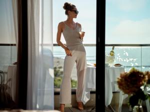 Baltivia Sea Resort في ميلنو: امرأة ترتدي بدلة بيضاء تقف أمام النافذة
