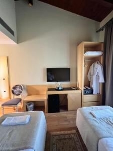 a bedroom with two beds and a desk with a tv at Kodra e Kuajve in Durrës