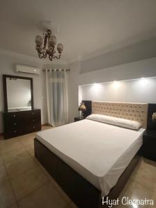 a bedroom with a large white bed and a mirror at Hyat Cleopatra Suites in Alexandria