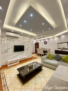 Hyat Cleopatra Suites في الإسكندرية: غرفة معيشة مع أريكة وتلفزيون على الحائط