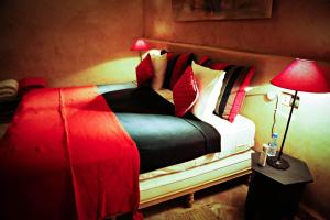 sypialnia z łóżkiem z białymi i czerwonymi poduszkami w obiekcie Le moulin w mieście Tarudant