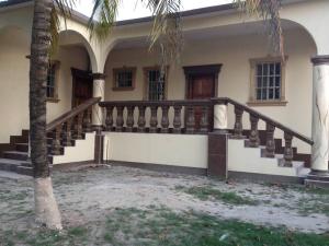 a house with stairs and a palm tree in front of it at Banyan Rose in Orange Walk