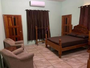 a bedroom with a bed and a couch and a chair at Banyan Rose in Orange Walk
