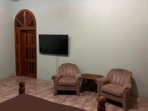 a living room with two chairs and a tv at Banyan Rose in Orange Walk
