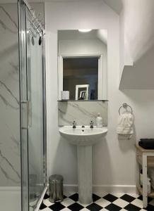 a white bathroom with a sink and a shower at The Studio in the Annex in Potters Bar