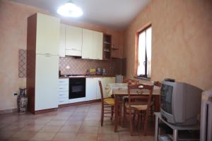 a kitchen with white cabinets and a table and a television at Casa Vacanze Korello in Gasponi