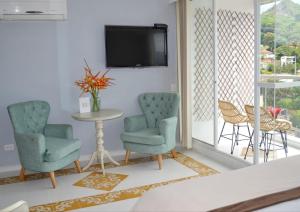 - un salon avec 2 chaises, une table et une télévision dans l'établissement Hotel Mediterraneo Boutique, à Villeta