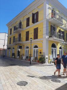 two people walking in front of a yellow building at Hotel Princ in Shkodër