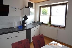 eine Küche mit einer Theke, einer Spüle und 2 Stühlen in der Unterkunft Ferienwohnung mit Ausblick in Wimmelburg in Wimmelburg