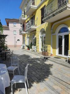 un bâtiment jaune avec des tables et des chaises devant lui dans l'établissement Hotel Princ, à Shkodër