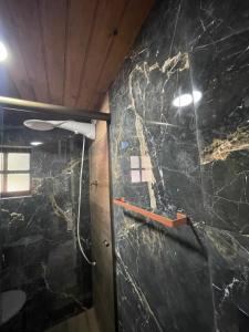 y baño con ducha y pared de mármol negro. en Chale Sabrina, en Campos do Jordão