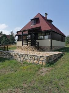 a house with a stone retaining wall in front of it at Zeleni Breg in Zlatibor