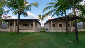 una casa con dos palmeras en el patio en Condominio Praia Caraubas, en Caraúbas