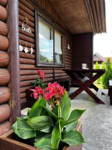 un porche de una cabaña de madera con una mesa y flores en Dom Pod Długim Wiosłem, en Wiartel