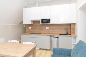 cocina con armarios blancos y sofá azul en VacationClub – Zdrojowa 7 Apartament 8 en Duszniki Zdrój