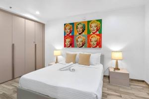 ein Schlafzimmer mit einem weißen Bett und einem Gemälde an der Wand in der Unterkunft Ocean Drive direct beach access South of Fifth Apartment in Miami Beach