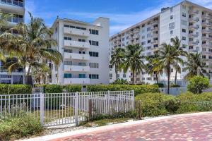 einen weißen Zaun vor einem Gebäude mit Palmen in der Unterkunft Ocean Drive direct beach access South of Fifth Apartment in Miami Beach