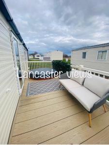 a wooden deck with a couch on a house at Lancaster Views, Luxury 2022 home with Hot Tub in Tattershall