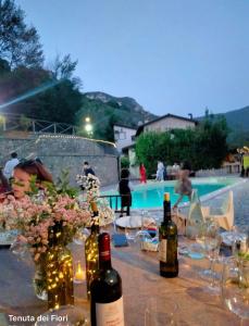 a table with wine bottles and flowers next to a swimming pool at La Tenuta dei Fiori in Ferentillo