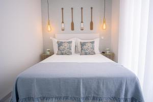 um quarto com uma cama branca com lençóis e almofadas azuis em Villa Beach em Nazaré