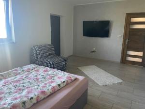 a bedroom with a bed and a chair and a television at Lawendowy apartament in Mszana Dolna