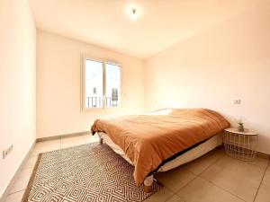 a bedroom with a bed and a window and a rug at Appartement Neuf avec Terrasse in Saint-Florent
