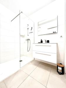 uma casa de banho branca com um chuveiro e um lavatório. em Appartement Neuf avec Terrasse em Saint-Florent