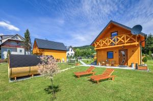 a wooden house with two benches in the yard at Domek całoroczny in Tylicz