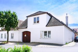 une maison blanche avec une porte rouge dans l'établissement Chill & Relax Apartments Purbach, à Purbach am Neusiedlersee