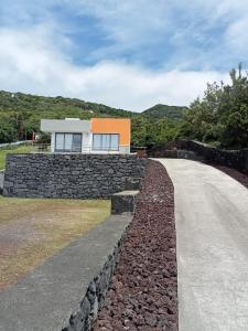 a house on a stone wall next to a road at Casa da Bella in Velas
