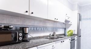 une cuisine avec un évier et un micro-ondes dans l'établissement Adaptado y cómodo apartamento en Iturrama, à Pampelune