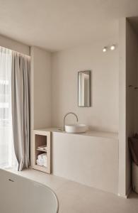a white bathroom with a sink and a mirror at Enso District Hotel in Knokke-Heist