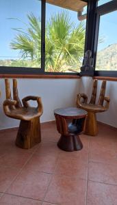 three wooden chairs and a table and a window at La Foggia seaside paradise in Siculiana